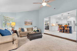 Carpeted living room with high vaulted ceiling and ceiling fan