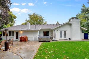 Rear view of house with french doors, a lawn, a patio area, and a hot tub