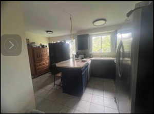 Kitchen with light tile patterned floors, blue cabinetry, stainless steel refrigerator, a kitchen breakfast bar, and kitchen peninsula