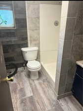 Bathroom with hardwood / wood-style flooring, walk in shower, vanity, and toilet