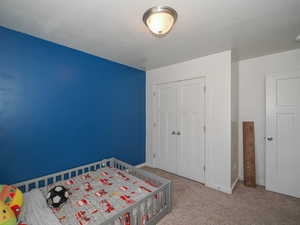 Unfurnished bedroom featuring a closet, light colored carpet, and a textured ceiling