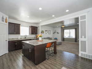 Kitchen featuring a center island, a kitchen breakfast bar, sink, backsplash, and dark hardwood / wood-style floors