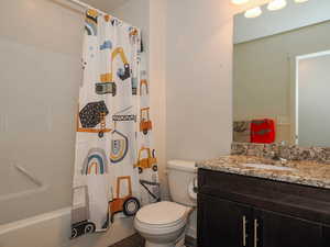 Full bathroom with toilet, vanity, and shower / bath combination with curtain