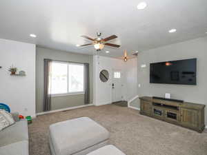 Carpeted living room with ceiling fan and a textured ceiling