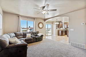 Living room featuring ceiling fan with notable chandelier, sink, a textured ceiling, and light tile patterned flooring