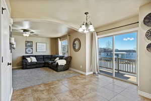 Living room featuring a water view, ceiling fan with notable chandelier, and light carpet