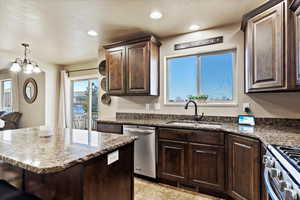 Kitchen featuring pendant lighting, dark brown cabinetry, stainless steel appliances, dark stone countertops, and sink