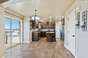 Kitchen with dark brown cabinetry, a center island, decorative light fixtures, stainless steel appliances, and a kitchen breakfast bar