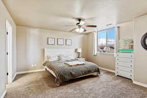 Carpeted bedroom with ceiling fan and a textured ceiling