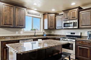 Kitchen featuring sink, dark brown cabinets, dark stone counters, and appliances with stainless steel finishes