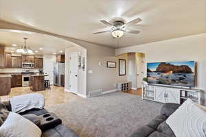 Carpeted living room with ceiling fan with notable chandelier