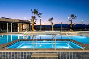 Pool at dusk with a mountain view and a hot tub