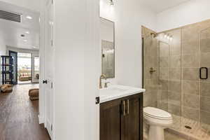 Bathroom with hardwood / wood-style floors, toilet, vanity, and an enclosed shower