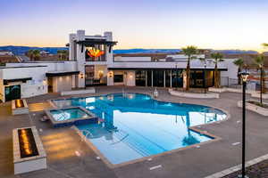 Pool at dusk featuring a mountain view, a community hot tub, and a patio area