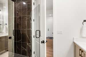 Bathroom featuring vanity, walk in shower, and wood-type flooring