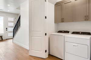 Laundry room with light hardwood / wood-style floors, cabinets, and independent washer and dryer