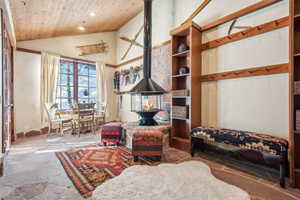 Living area featuring vaulted ceiling, wooden ceiling, and a wood stove