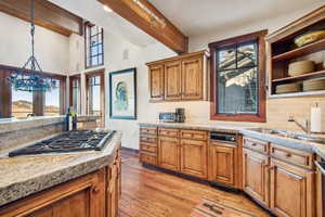 Kitchen with tasteful backsplash, appliances with stainless steel finishes, sink, and beam ceiling