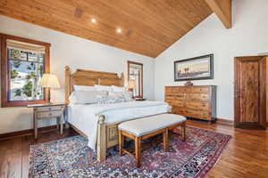 Bedroom featuring dark hardwood / wood-style flooring, vaulted ceiling with beams, and wooden ceiling