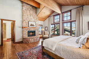 Bedroom featuring beamed ceiling, wood-type flooring, wood ceiling, and a fireplace