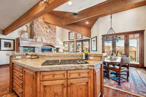 Kitchen with beamed ceiling, stainless steel gas cooktop, pendant lighting, and dark hardwood / wood-style floors