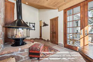 Interior space with beamed ceiling, a wood stove, and wooden ceiling