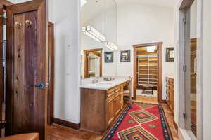 Bathroom featuring lofted ceiling, vanity, wood-type flooring, and a shower with shower door