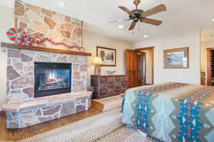 Bedroom with hardwood / wood-style floors, a fireplace, and ceiling fan