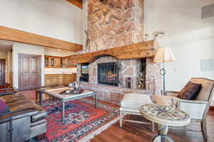 Living room featuring wood-type flooring, a fireplace, and a high ceiling