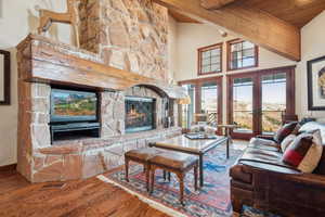 Living room featuring a stone fireplace, wood ceiling, high vaulted ceiling, beamed ceiling, and hardwood / wood-style floors