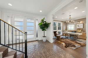 Entryway with an inviting chandelier, crown molding, and dark hardwood / wood-style flooring