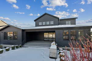 Snow covered back of property with a porch and a garage