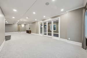 Basement with crown molding, light carpet, and french doors