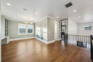 Interior space featuring a textured ceiling, dark hardwood / wood-style floors, ornamental molding, and a notable chandelier