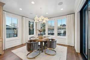 Dining area featuring crown molding, dark wood-type flooring, a notable chandelier, and a wealth of natural light