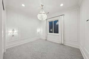 Carpeted empty room with a notable chandelier and ornamental molding