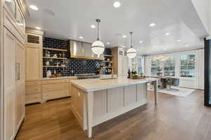 Kitchen with sink, extractor fan, pendant lighting, and a large island with sink