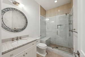 Bathroom featuring vanity, toilet, walk in shower, and tile patterned floors