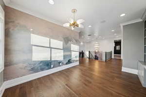 Empty room with crown molding, dark hardwood / wood-style floors, and a notable chandelier