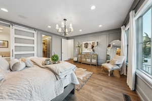 Bedroom with multiple windows, hardwood / wood-style flooring, a walk in closet, and a barn door