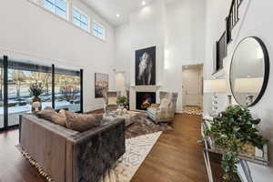 Living room featuring a towering ceiling, a wealth of natural light, and hardwood / wood-style flooring