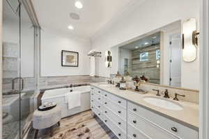 Bathroom with hardwood / wood-style floors, independent shower and bath, vanity, and ornamental molding