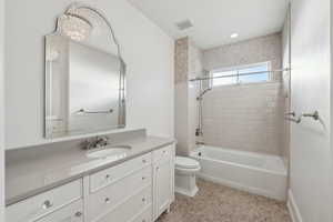 Full bathroom with toilet, vanity, tiled shower / bath combo, and tile patterned flooring