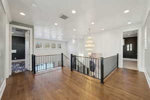 Corridor with hardwood / wood-style flooring and a chandelier