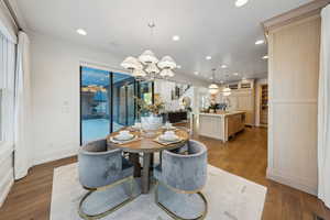 Dining area with sink, a chandelier, ornamental molding, and dark hardwood / wood-style flooring