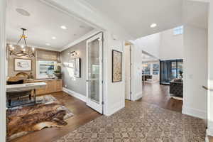 Interior space with hardwood / wood-style flooring, a chandelier, and ornamental molding