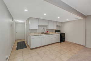 Kitchen featuring sink, range with electric cooktop, white cabinetry, and light tile patterned floors