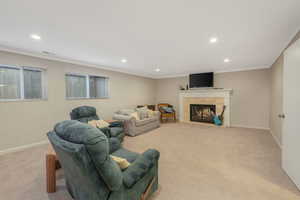 Carpeted living room featuring ornamental molding and a tiled fireplace