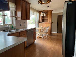 Kitchen featuring sink, decorative light fixtures, light wood-type flooring, stainless steel appliances, and backsplash