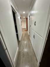 Corridor with ornamental molding and light hardwood / wood-style flooring